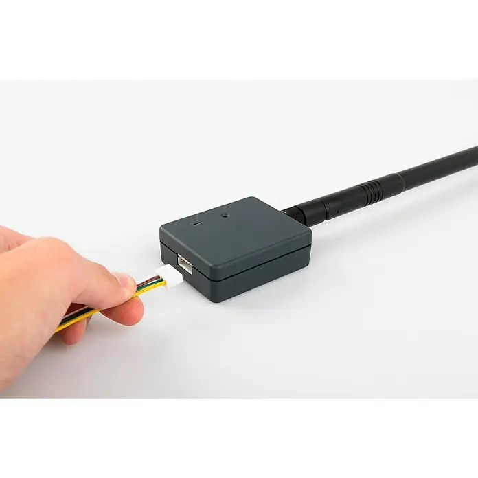 Schellenberg Smartphone-Garagentoröffner Powerlift - Passend für: Schellenberg Garagentorantriebe - Ein graues, rechteckiges Gerät mit Antenne und ein Kabel, das von einer Hand eingesteckt wird.