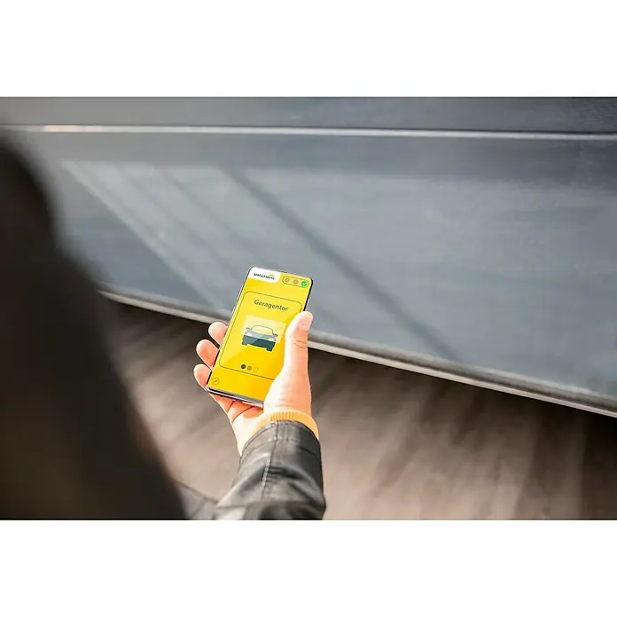 Schellenberg Smartphone-Garagentoröffner Powerlift - Passend für: Schellenberg Garagentorantriebe - Person hält ein Smartphone mit der Garagentor-App von Schellenberg in der Hand. Die App ist gelb und zeigt ein Autosymbol.