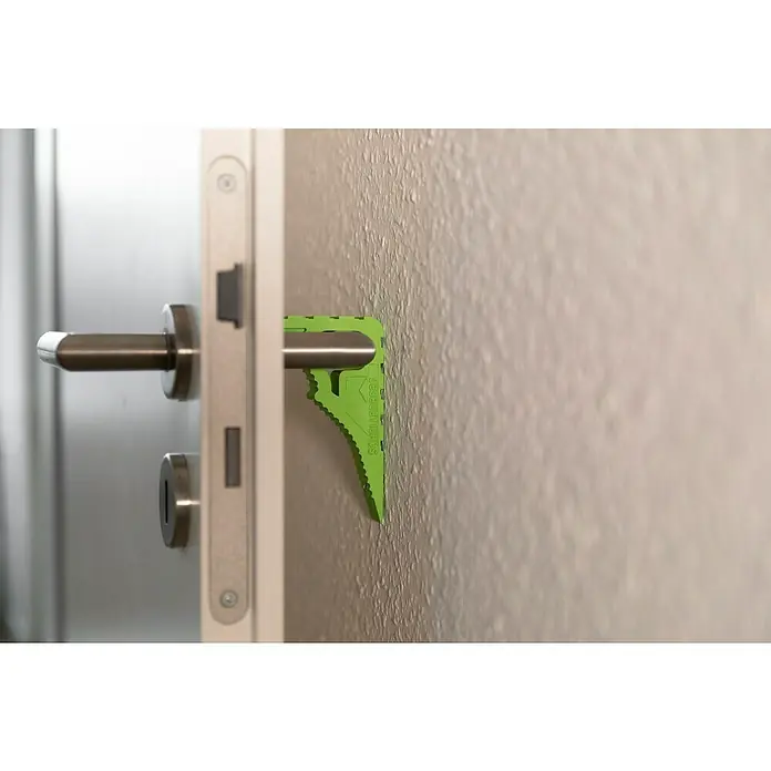 Schellenberg Tür- & Fensterstopper - Grün - Tür mit Türgriff und einem grünen Türstopper. Der Türstopper ist zwischen Türgriff und Wand platziert.