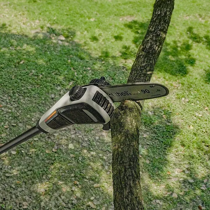 Litheli U20 Akku-Hochentaster - Ohne Akku, Schwertlänge: 200 mm, Länge Stiel: 340 cm - Eine Akku-Kettensäge bei der Arbeit. Die Kettensäge ist weiß und schwarz und schneidet einen Baumstamm.
