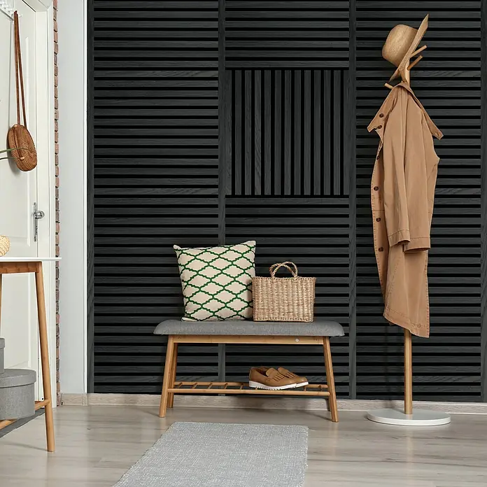 FibroTech Akustikpaneel SQUARE - Black Oak, 520 x 520 x 22 mm - Eine stilvolle Eingangsdiele mit schwarzer Wandverkleidung, Bank, Kleiderständer und passenden Accessoires. Elegantes Design für einen einladenden Empfang.