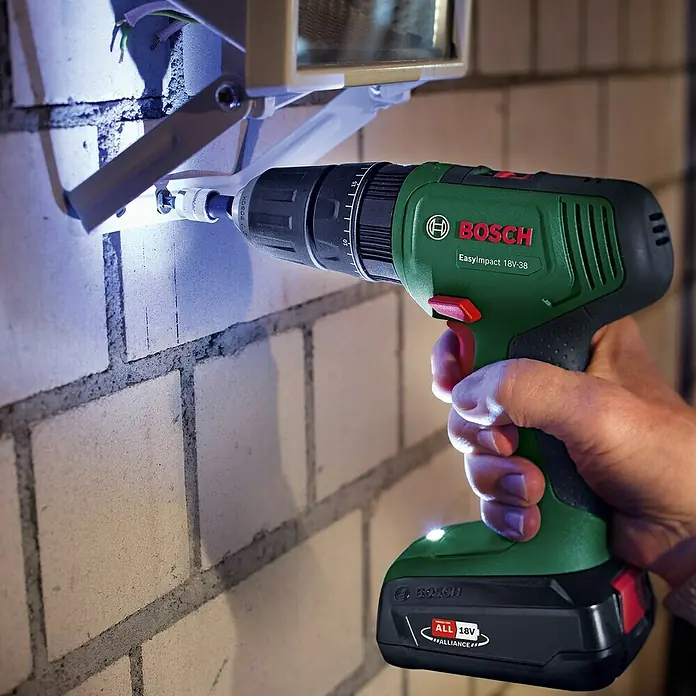 Bosch Power for All 18V Akku-Schlagbohrschrauber EasyImpact 18V-38 - 18 V, 1 Akku, 2,5 Ah, 38 Nm - Ein Akkuschrauber der Marke Bosch wird verwendet, um eine Schraube in eine Ziegelwand zu drehen. Ideal für Heimwerkerarbeiten.