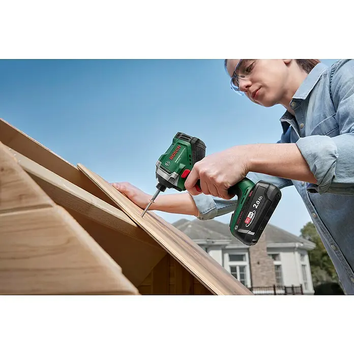 Bosch Power for All 18V Akku-Drehschlagschrauber UniversalImpactDrive 18V-210 - 18 V, Ohne Akku, 210 Nm - Nahaufnahme einer Frau, die mit einem Bosch Akku-Schlagschrauber ein Holzstück befestigt. Der grüne Schrauber mit 2.0 Ah Akku ist gut sichtbar.