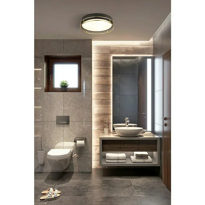 Searchlight Deckenleuchte rund Phoenix - 60 W, Ø x H: 30 x 9,5 cm, Schwarz/ Gold - Ein Badezimmer mit grauen Fliesen, einer runden Deckenleuchte und einem Waschtisch mit Holzdetails.