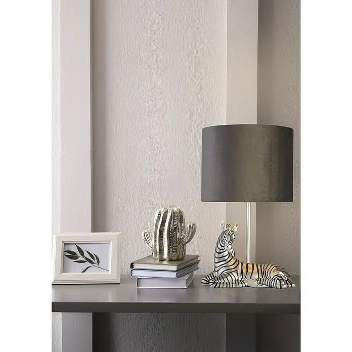 Searchlight Tischleuchte Zebra - 7 W, L x B x H: 20 x 20 x 35 cm, Silber, Schwarz, E27 - Dekorative Szene mit einer Zebra-Figur, einem Kaktus auf Büchern und einem Fotorahmen, elegant arrangiert auf einer grauen Oberfläche.