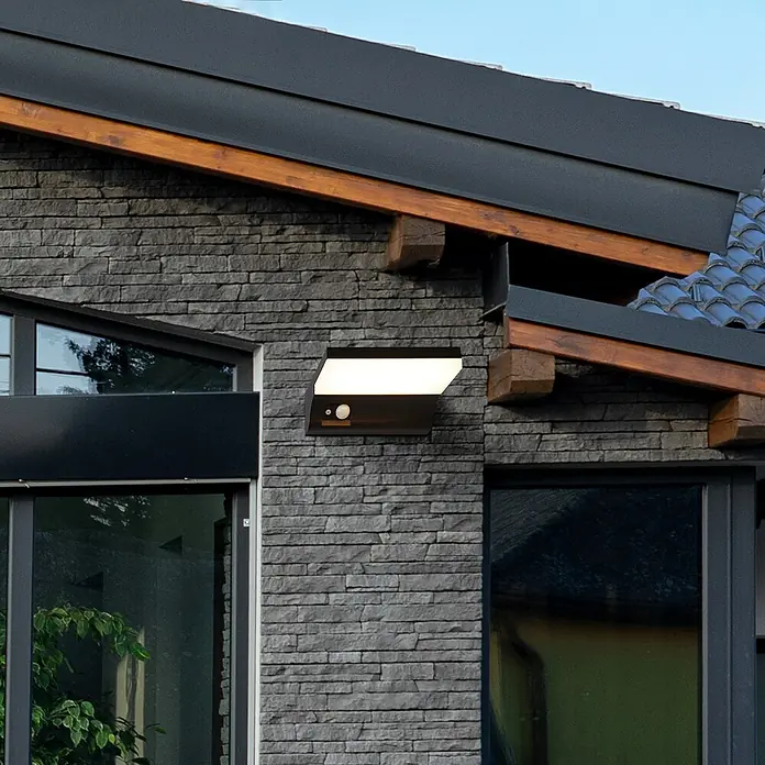 Searchlight Solar-Außenwandleuchte - 2 W, L x B x H: 16 x 16 x 6 cm, Schwarz, IP54 - Moderne Außenleuchte mit Bewegungsmelder an einer grauen Steinwand. Das schlichte Design passt gut zur Hausfassade.