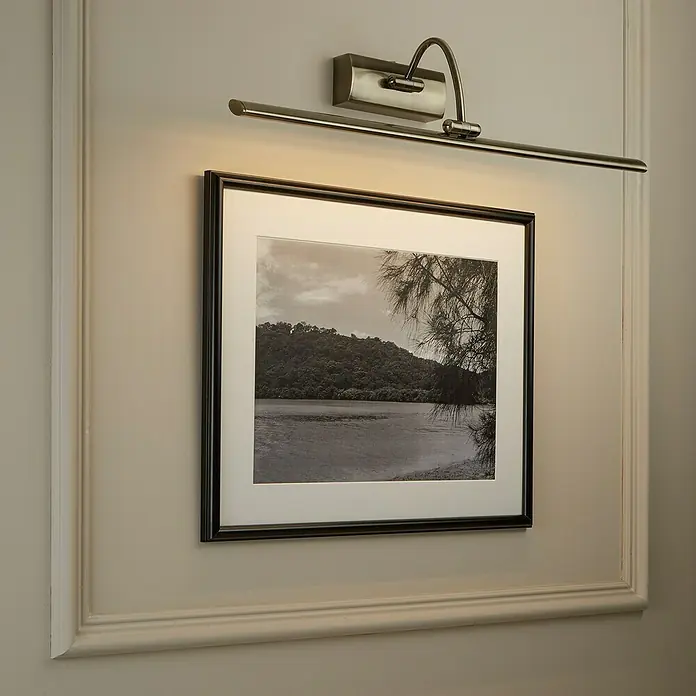 Searchlight LED-Bilderleuchte Barcelona - 15 W, L x B x H: 64 x 11 x 11 cm, Messing - Wandmontierte Bilderleuchte aus Metall, die ein gerahmtes Schwarzweißfoto mit Landschaftsmotiv beleuchtet. Das Licht erzeugt einen warmen Schein auf dem Bild.