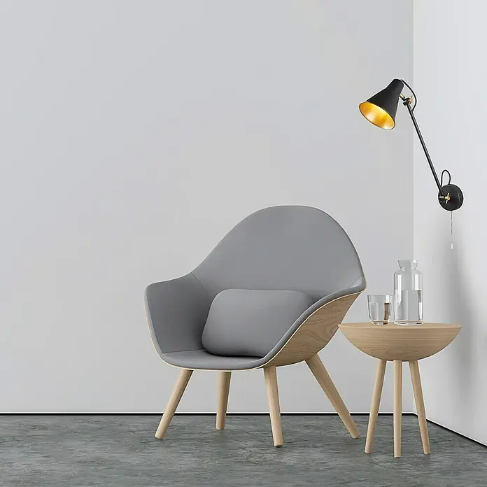 Searchlight Wandleuchte Swing Arm - 60 W, L x B x H: 14 x 14 x 39 cm, Schwarz/ Gold - Das Bild zeigt einen grauen Sessel mit Kissen, einen Beistelltisch mit Wasserflasche und ein elegantes Wandlampe, die eine gemütliche Atmosphäre schaffen.