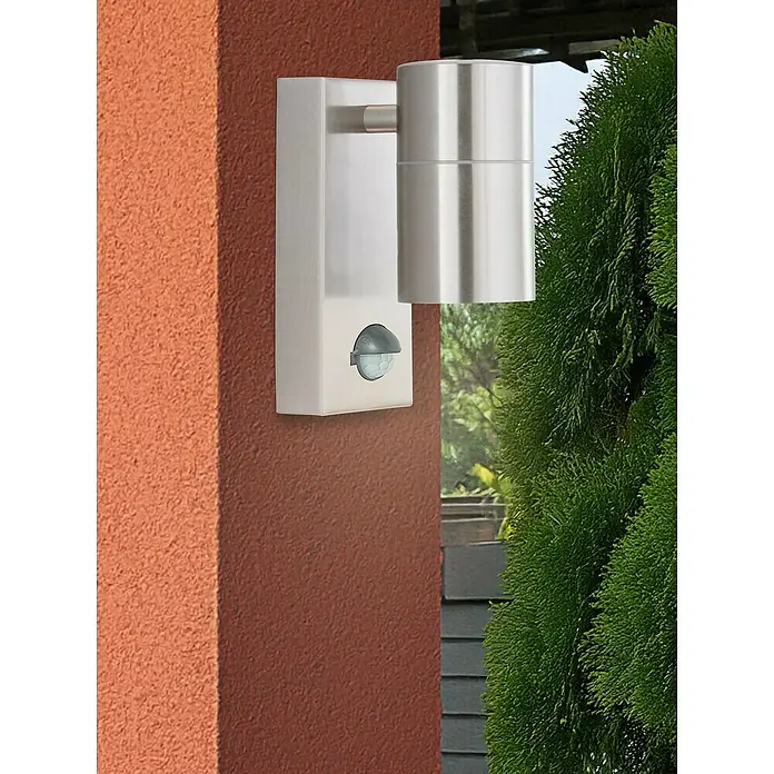 Searchlight LED-Außenwandleuchte Metro - 35 W, 7 x 7 x 15 cm, Edelstahl, IP44 - Eine moderne Außenleuchte aus Edelstahl mit Bewegungsmelder an einer roten Wand. Stilvolle Beleuchtung für den Außenbereich.