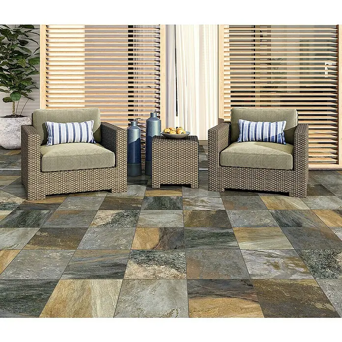Pavimento efecto piedra Albarracin - 33,3 cm x 33,3 mm, Terracota - Agradable disposición de patio con dos sillones de mimbre, cojines a rayas azules y una mesa auxiliar sobre suelo de baldosas.