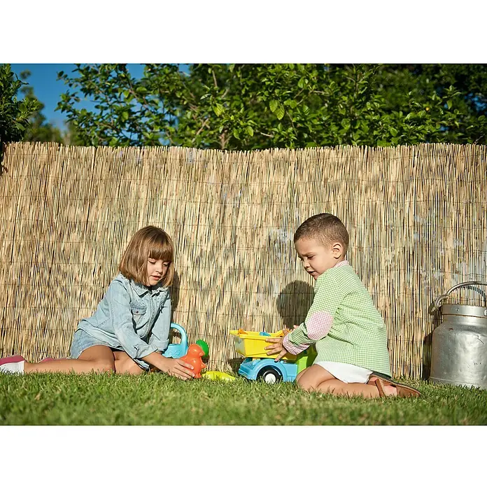 Faura Ocultación de bambú - L x Al: 1,5 x 5 m - Dos niños juegan en el jardín con un camión de juguete y otros juguetes frente a una cerca de bambú.