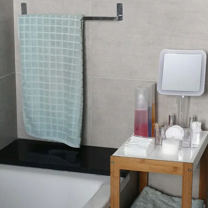 Deblanch Toallero de barra adhesivo Vento 40 - L x An x Al: 65 x 40 x 5 cm, Acero, Cromo - Escena de baño con toallero, toalla y una pequeña mesa con artículos de baño, como un espejo y bastoncillos de algodón.