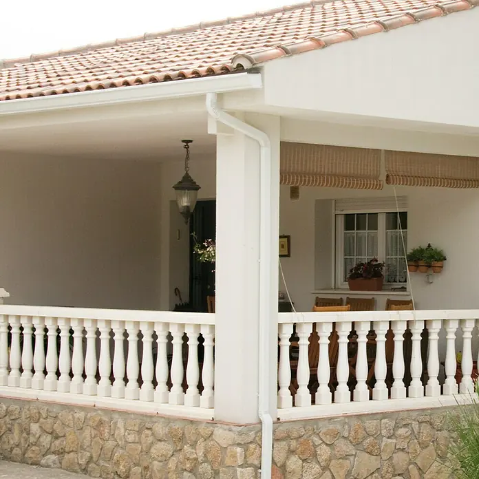 Balaustrada Italia 90 - 12 x 12 x 90 cm, Blanco, Hormigón - Imagen de un porche cubierto con balaustradas blancas y cimientos de piedra rústica, creando un espacio exterior acogedor.