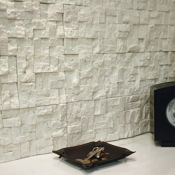 Revestimiento de piedra Trencadis Hueso - 30 x 15 x 2 cm - Primer plano de una bandeja de cuero con llaves y monedas sobre una superficie blanca contra una pared texturizada.