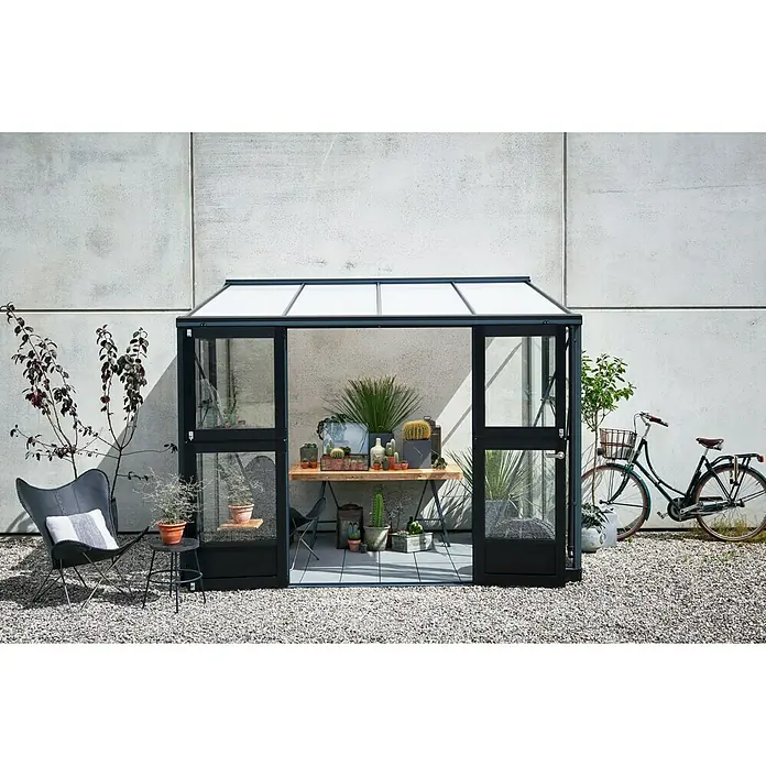 Juliana Gewächshaus Veranda - Außenmaß inkl. Dachüberstand (B x T): 221 x 296 cm, Material Seitenwand: Glas, 3 mm, Anthrazit - Ein Gewächshaus mit Pflanzen und einem Tisch, der mit Kakteen und Blumentöpfen geschmückt ist, schafft eine grüne Oase im Freien.