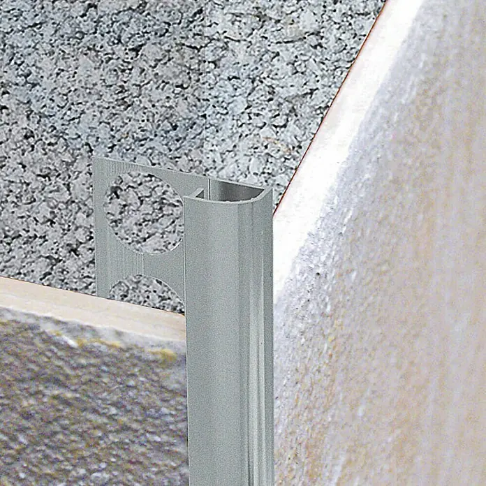 Perfil para baldosas 171 A - Aluminio, Plateado, 2,5 m x 12 mm - Primer plano de un perfil de azulejo plateado en una pared. Ideal para baños o cocinas, ofreciendo bordes limpios y protección.