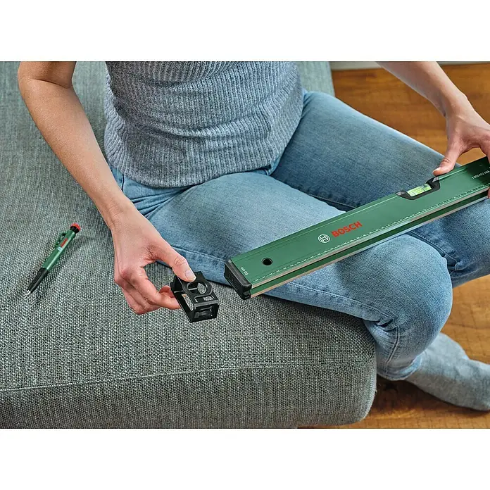 Bosch Wasserwaage - Länge: 60 cm, Anzahl Libellen: 2 Stk. - Eine Person sitzt mit einer Bosch Wasserwaage und einem Winkelaufsatz.