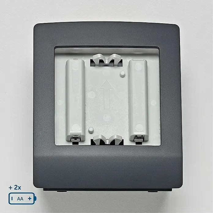 Homematic IP Halterung Tischaufsteller HmIP-DS55-A - Batteriebetrieben, 7,9 x 9 x 6,7 cm, Anthrazit - Graue quadratische Batteriehalterung für zwei AA-Batterien. Das Innere ist hellgrau mit einer Richtungspfeilmarkierung.