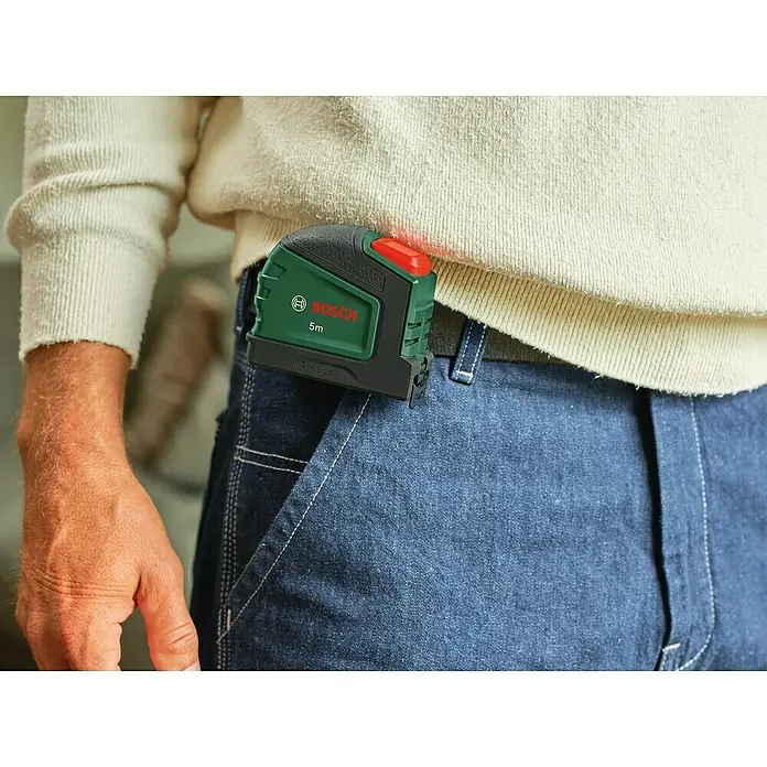 Bosch Bandmaß - 5 m - Nahaufnahme einer Person mit einem Bosch 5m Entfernungsmesser am Hosenbund. Perfekt für genaue Messungen bei jedem Projekt.