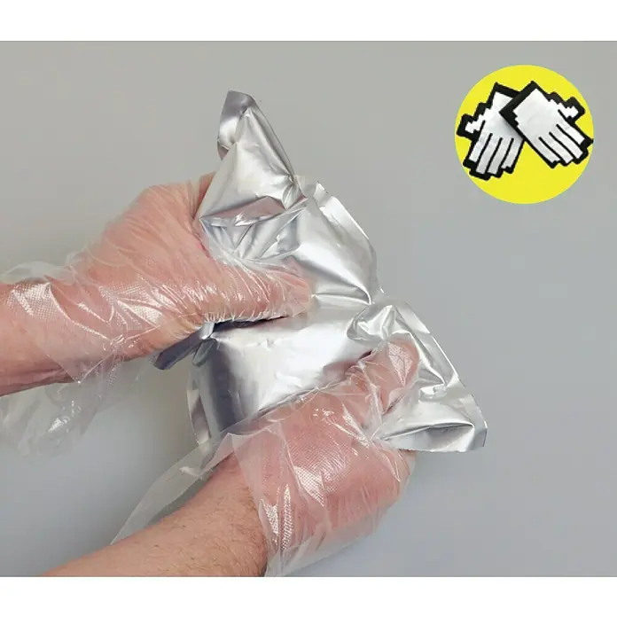 Kaiser Feuchtraum-Abzweigdose Installations-Set Outdoor IP68BOX - 95 x 95 x 55 mm, Aufputz, IP68 - Nahaufnahme von Händen mit Schutzhandschuhen, die eine versiegelte, silberfarbene Verpackung halten.