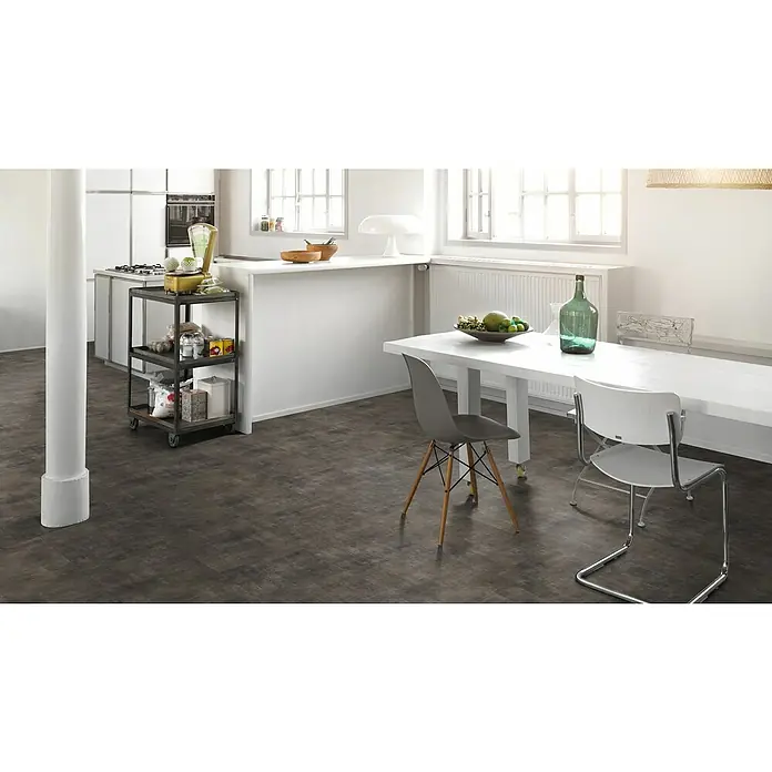 Parador Vinylboden Basic 5.3 - Mineral black, Fliese, 914 x 457 x 5,3 mm - Einrichtung mit hellem Esstisch, Stühlen und einem Rollwagen mit Küchenutensilien. Der dunkle Boden bildet einen schönen Kontrast zum hellen Interieur.