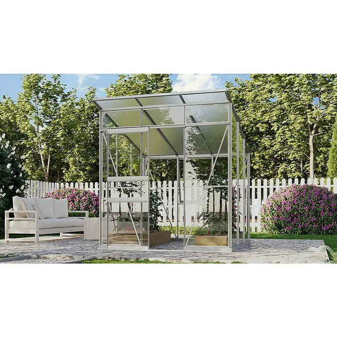 Vitavia Gewächshaus Fokus Glas - Material Seitenwand: Glas, Außenmaß inkl. Dachüberstand (B x T): 2.294 x 1.958 cm, Aluminium - Ein Gewächshaus mit klaren Scheiben steht im Garten und bietet einen sonnigen Platz für Pflanzen. Eine Couch lädt zum Verweilen ein.