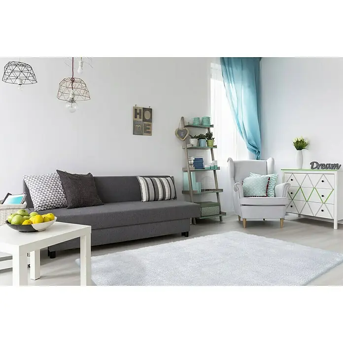Kayoom Hochflorteppich Bali - Puderblau, 290 x 200 cm, 100 % Polyester - Wohnzimmer mit grauem Sofa, weißem Teppich, Sessel und Kommode mit dekorativen Elementen und Lampen für ein modernes Ambiente.