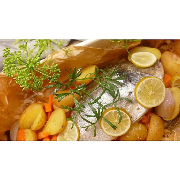 Blu Bio Meerfenchel - Crithmum maritimum, Topfgröße: 12 cm - Nahaufnahme von gebackenem Fisch mit Zitronen und Kräutern, serviert auf einem Teller mit Kartoffeln und Karotten, fertig zum Genießen.