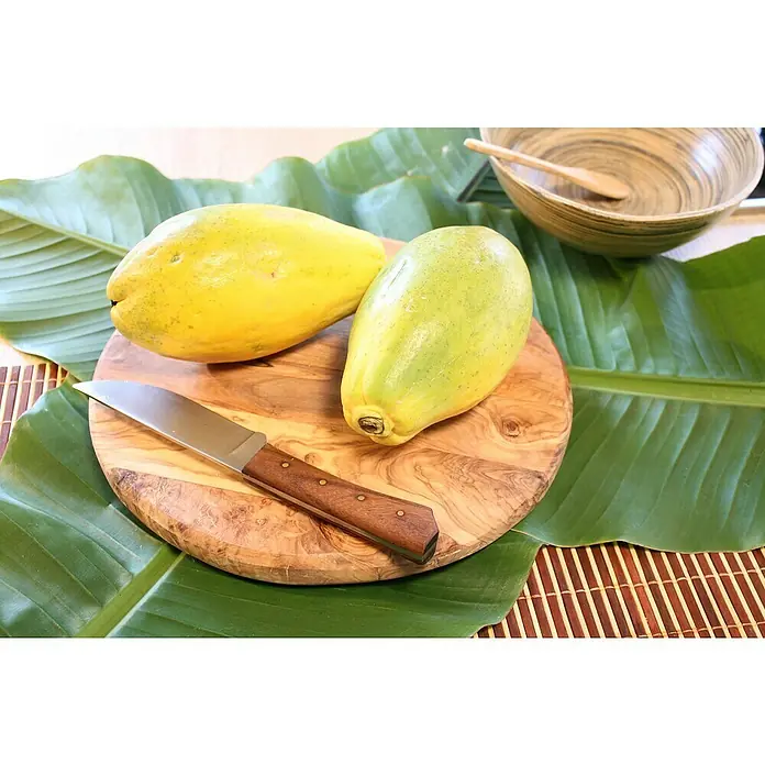 Blu Bio Papaya - Carica papaya, Topfgröße: 12 cm - Zwei saftige Papayas auf einem Holzbrett mit einem Messer, bereit zum Genießen, umgeben von dekorativen Blättern.