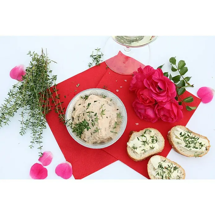 Blu Bio Rosenthymian - Thymus ssp., Topfgröße: 12 cm - Nahaufnahme von Brot mit Dip, garniert mit Kräutern, auf einem roten Tuch, begleitet von Rosen und einem Glas Wein.