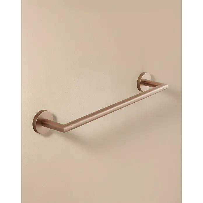 Cosmic Toallero de barra Dual Start - 40 cm, Cobre - Una barra de toalla moderna de oro rosa montada en una pared beige claro, mostrando su diseño minimalista y elegante.