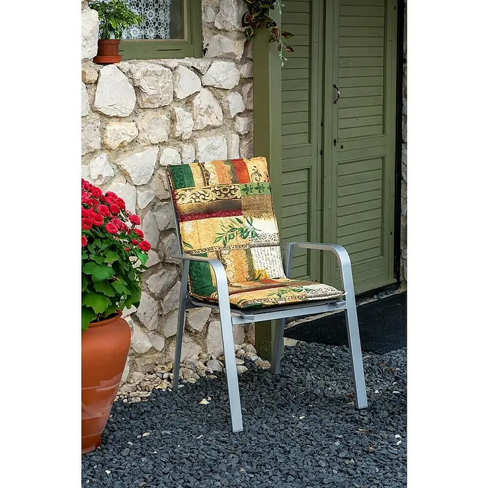 beo Gartenmöbel-Auflage Glasgow - Hochlehner, 6 Stk., L x B x H: 100 x 48 x 5 cm, Baumwolle, Poylester, Gelb/Grün - Ein bequemer Gartenstuhl mit bunter Polsterung steht vor einer Steinmauer und einer grünen Tür, umgeben von Pflanzen.