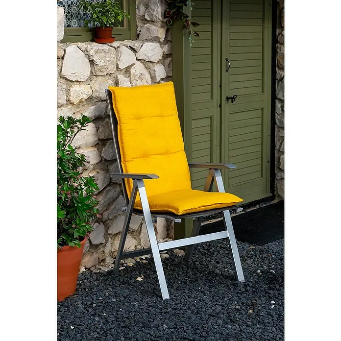beo Gartenmöbel-Auflage Brovine - Hochlehner, 4 Stk., L x B x H: 118 x 50 x 6 cm, Baumwolle, Polyester, Gelb - Dieser graue Klappstuhl mit gelbem Kissen lädt zum Entspannen ein. Der Stuhl steht vor einer Steinmauer und einer grünen Tür.