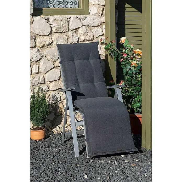 beo Gartenmöbel-Auflage - Relaxsesselauflage, 1 Stk., L x B x H: 171 x 46 x 8 cm, Baumwolle, Polyester, Anthrazit - Die graue Liege mit Polster steht einladend im Garten, umgeben von Steinen, Pflanzen und einer malerischen Steinmauer.