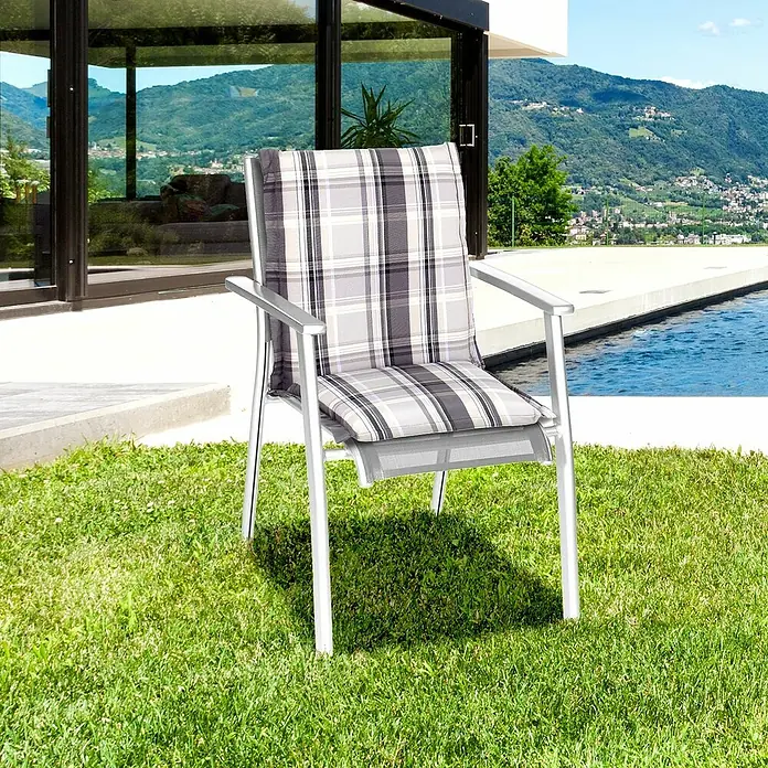 beo Gartenmöbel-Auflage Atika - Niederlehner, 6 Stk., L x B x H: 100 x 52 x 8 cm, Dralon, Polyester, Grau/Weiß - Ein Gartenstuhl mit einem karierten Kissen steht auf dem Rasen vor einem modernen Haus mit Pool.