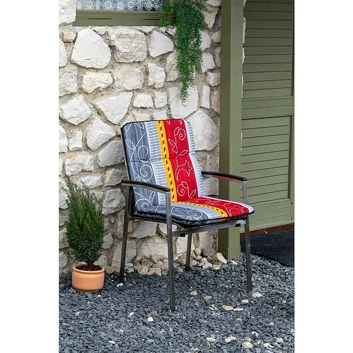 beo Gartenmöbel-Auflage Elmira - Niederlehner, 4 Stk., L x B x H: 96 x 47 x 5 cm, Baumwolle, Polyester, Rot/Grau/Gelb - Bild eines Stuhls mit farbenfrohem Kissen vor einer Steinmauer.