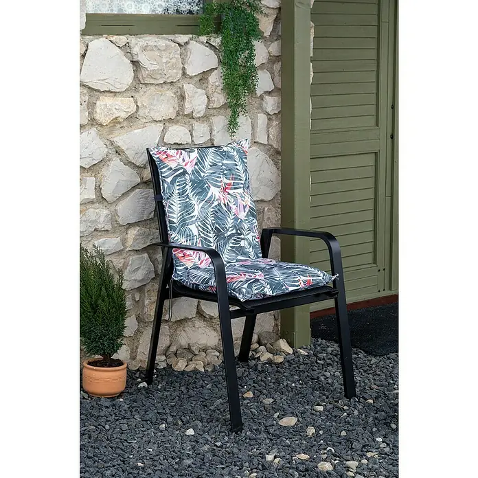 beo Gartenmöbel-Auflage Tamky - Niederlehner, 6 Stk., L x B x H: 98 x 46 x 8 cm, Baumwolle, Polyester, Rosa/Blau - Eine Nahaufnahme eines schwarzen Stuhls mit einem blaugrün-roten Palmenblattkissen vor einer Steinmauer und einer grünen Tür.