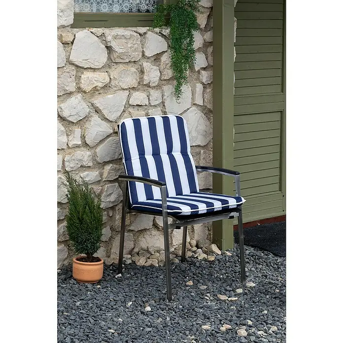beo Gartenmöbel-Auflage Paselista - Niederlehner, 6 Stk., L x B x H: 96 x 47 x 5 cm, Baumwolle, Polyester, Blau/Weiß - Ein blauer und weiß gestreifter Stuhl mit Metallrahmen steht vor einer Steinmauer und grüner Tür, dekoriert mit einer kleinen Pflanze.