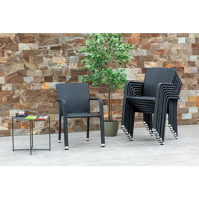Acamp Stapelsessel Carlos - 8 Stk., Aluminium, Kunststoff, Stapelbar, Schwarz, B x T x H: 57 x 64 x 84 cm - Ein schwarzer Rattansessel steht neben einem Stapel gleicher Sessel und einem Tisch mit Zeitschriften vor einer verzierten Wand.