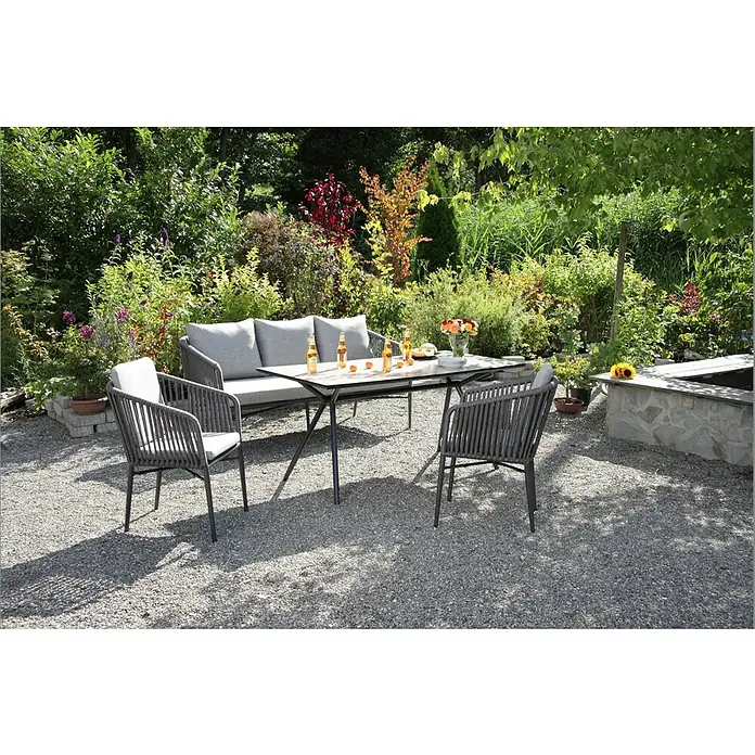 Acamp Gartenmöbel-Set Manhattan/Alpha - 4 -tlg., Aluminium, Polyester, Grau - Gartengestaltung mit grauer Loungegruppe, bestehend aus Sofa, Tisch, Stühlen, Bierflaschen und Blumenvase auf einem Kiesweg, umgeben von üppigem Grün.