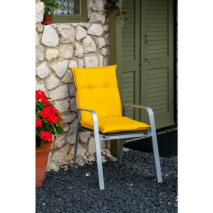 beo Gartenmöbel-Auflage Brovine - Niederlehner, 6 Stk., L x B x H: 101 x 50 x 6 cm, Baumwolle, Polyester, Gelb - Ein sonnengelber Stuhlkissenbezug auf einem silbernen Stuhl vor einer rustikalen Steinmauer. Perfekt für Garten und Terrasse.