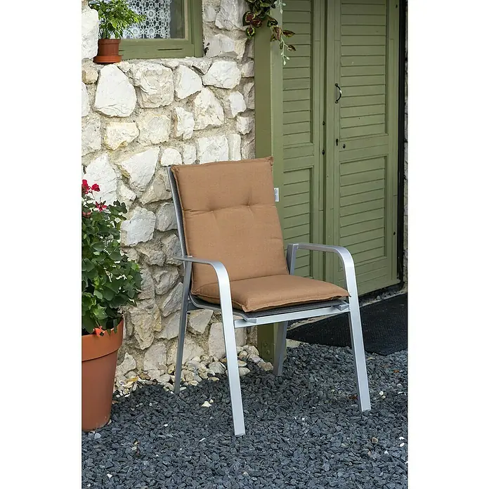 beo Gartenmöbel-Auflage Tolonaro - Niederlehner, 4 Stk., L x B x H: 98 x 46 x 8 cm, Baumwolle, Polyester, Braun - Bequemer Gartenstuhl mit braunem Kissen vor einer Steinfassade und grünen Fensterläden für entspannte Stunden im Freien.