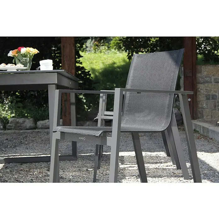 Acamp Gartenmöbel-Set Hollywood/Chicago - 7 -tlg., Aluminium, Acatex, Grau - Eine Nahaufnahme eines modernen grauen Gartenstuhls mit passendem Tisch auf einem Kiesweg, umgeben von Grün.