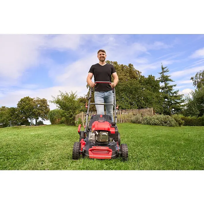 AL-KO Benzin-Rasenmäher Easy 4.66 SP-D - 2,4 kW, 149 cm³, Schnittbreite: 46 cm - Ein Mann mäht den Rasen mit einem roten und schwarzen AL-KO Rasenmäher vor einem grünen Garten. Der Rasenmäher ist das Hauptprodukt im Bild.