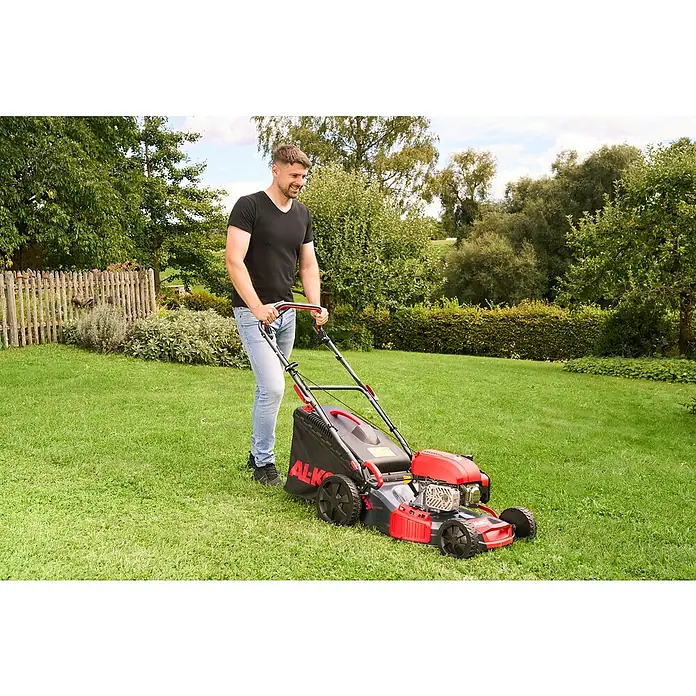 AL-KO Benzin-Rasenmäher Easy 4.66 SP-D - 2,4 kW, 149 cm³, Schnittbreite: 46 cm - Ein Mann mäht Rasen mit einem roten AL-KO Rasenmäher in einem grünen Garten.