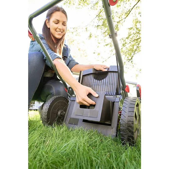 AL-KO Benzin-Rasenmäher Easy 5.16 SP-D - 2,6 kW, 171 cm³, Schnittbreite: 51 cm - Eine Frau befestigt den Fangkorb an einem Rasenmäher. Der Rasenmäher steht auf grünem Gras und die Frau lächelt.