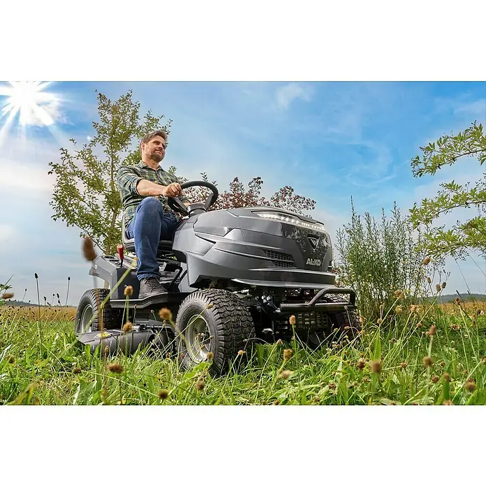 AL-KO Easy Rasentraktor 13-92.6 CS-A - 7,2 kW, Schnittbreite: 92 cm, Schnitthöhe: 30 mm - 90 mm, Kraftstoffart: Benzin - Ein Mann fährt einen AL-KO Aufsitzmäher durch hohes Gras, wobei die Maschine und ihre Geländetauglichkeit hervorgehoben werden.