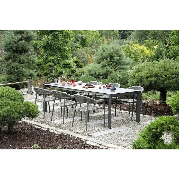 Acamp Gartenmöbel-Set Brooklyn/Woody - 7 -tlg., Aluminium, HPL, Anthrazit/Grau - Ein Gartentisch-Set mit grauem Tisch und passenden Stühlen in einem grünen Garten. Das Set bietet Platz für Mahlzeiten im Freien.