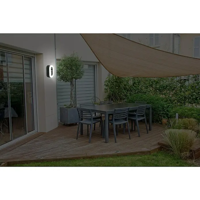 Lavida LED-Außenwandleuchte Oval - 11 W, 4,2 x 11,3 x 19 cm, Schwarz, IP65 - Eine moderne, runde Wandleuchte beleuchtet eine Terrasse mit Esstisch und Beschattungsegel. Stilvolle Außenbeleuchtung für gemütliche Stunden.