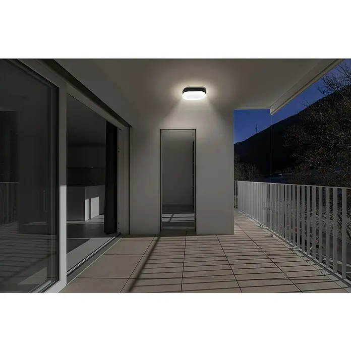 Lavida LED-Außenwandleuchte Oval - 11 W, 4,2 x 11,3 x 19 cm, Schwarz, IP65 - Moderne Deckenleuchte im Außenbereich eines Hauses. Die Leuchte spendet warmes Licht auf die Terrasse mit Fliesenboden.